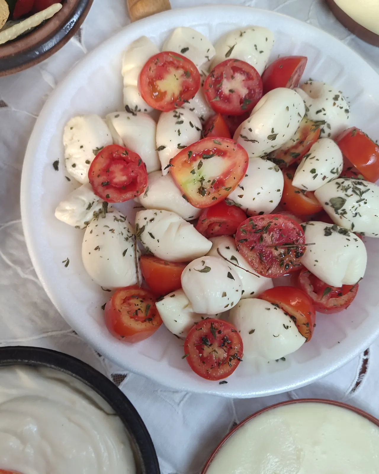 Bocconcini con tomate y orégano servidos en un plato blanco