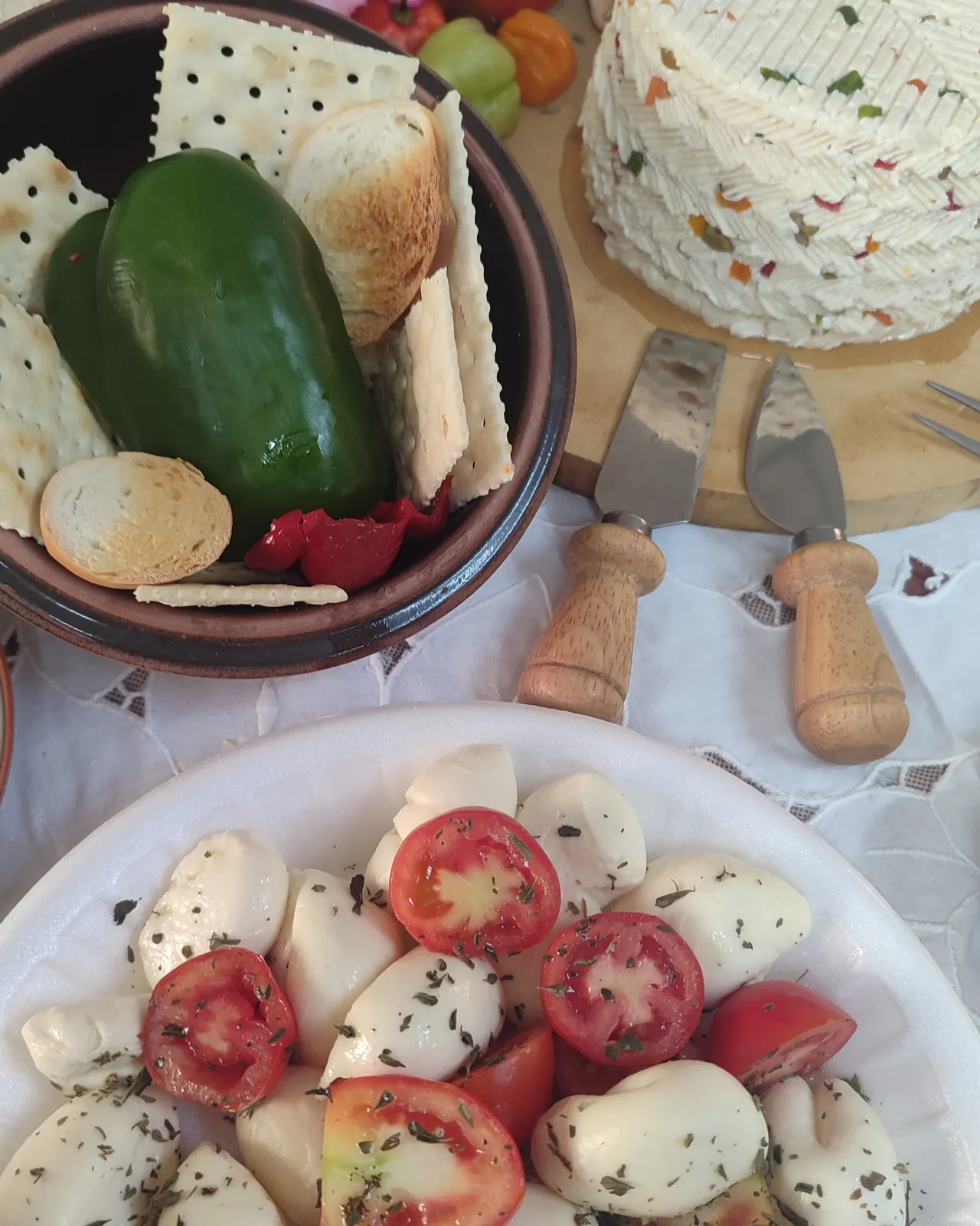 Queso aliñado con pimentón junto a galletas y un pimentón verde